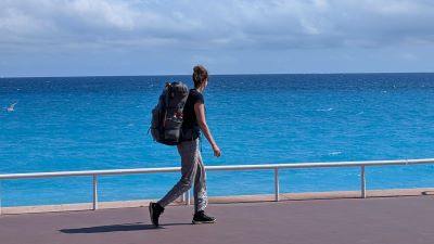 Person mit Rucksack auf dem Weg, im Hintergrund das Meer, Bild. zVg.