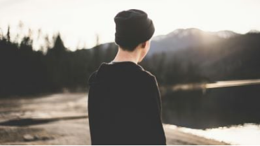 abgewandte Person in karger Landschaft - Symbolbild  